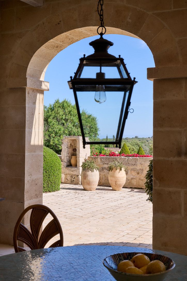 A lantern hanging in the arch, terracotta pots in the courtyard beyond