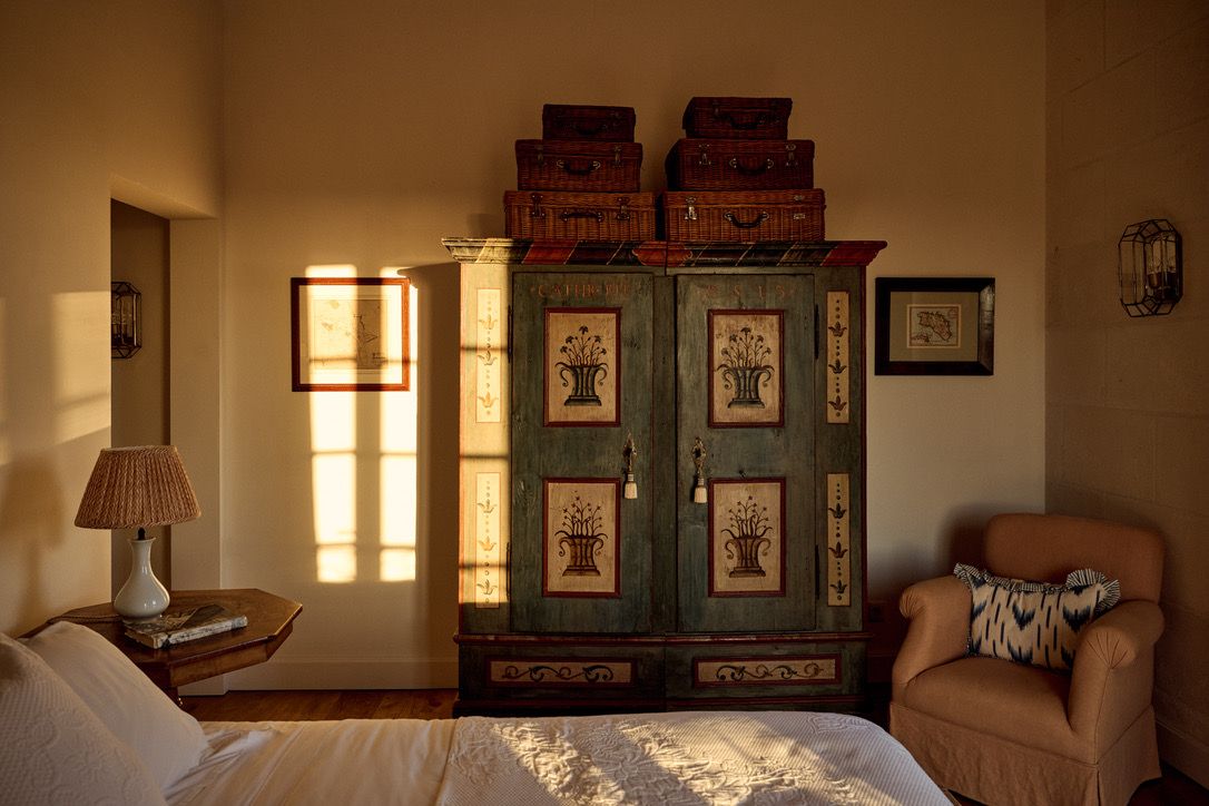 A painted wardrobe stacked with wicker cases in the evening light