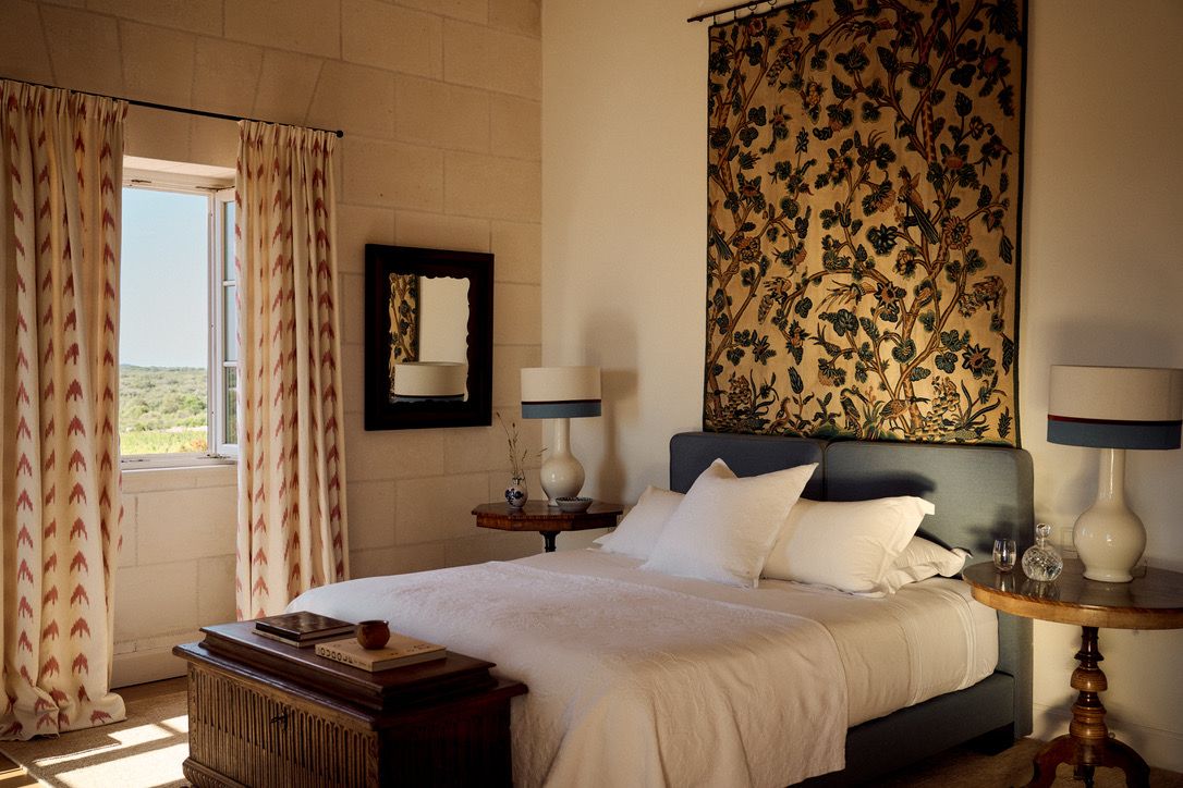 A bedroom hung with a crewelwork panel above the bed