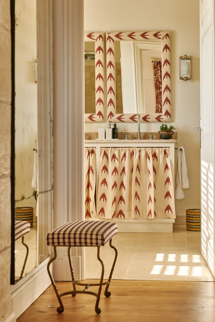 A bathroom with ikat-framed mirrors and skirted basin