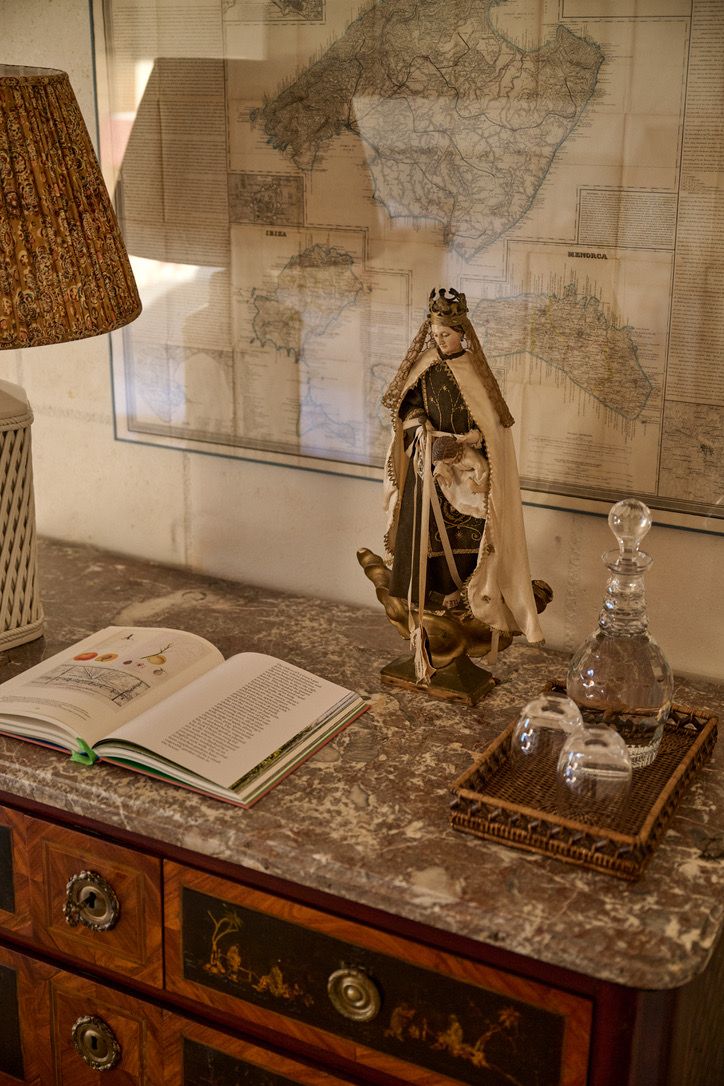 A dressed figure and decanter beneath an old map of the Balearics