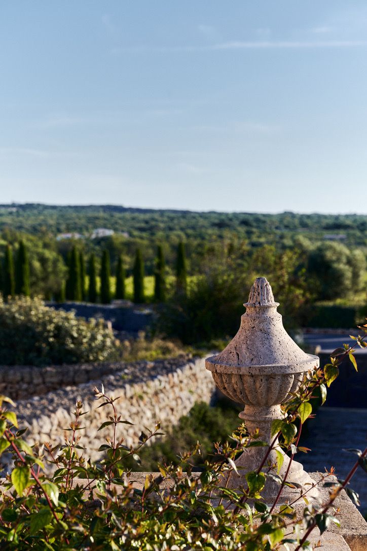 A stone finial on the balustrade, cypresses and countryside beyond